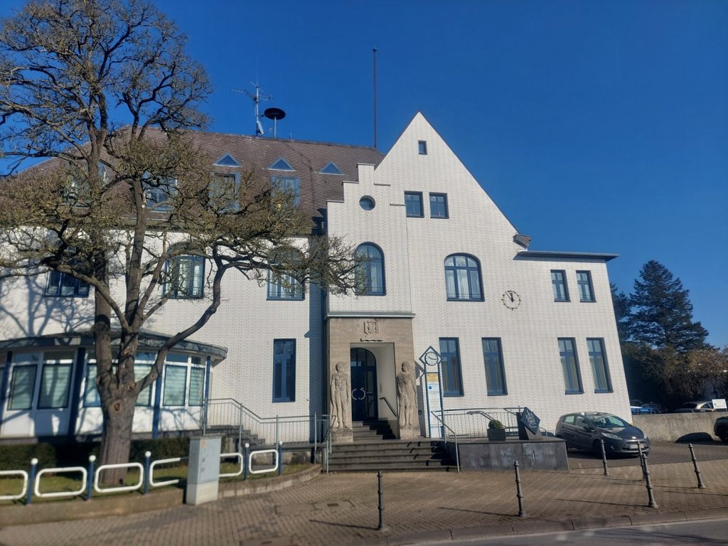 Außenansicht der Kinderarztpraxis in einem historischen Gebäude mit weißer Fassade und blauen Fenstern.